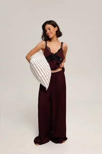 Detail of burgundy satin pajama set with black lace trim and wide-leg trousers