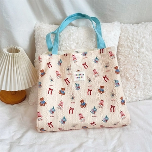 Detail of canvas bag with cute bear and rabbit prints on soft white bedding