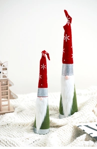Detail view of red and green Christmas gnomes with snowflake hats on cozy knit background