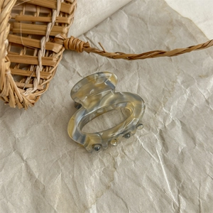 Detailed macro view of the marble pattern resin hair claw clip on aesthetic beige paper