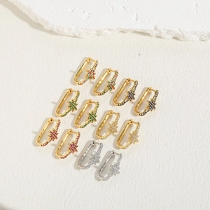 Close-up of geometric star earrings in gold and silver set with colorful zircons