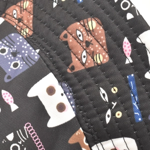 Détail du chapeau bob matelassé noir avec motifs de chats et poissons de dessin animé