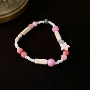 Makro-Detail von handgefertigtem Perlenarmband mit rosa Keramikperlen und Sternanhänger