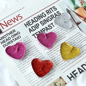 Macro shot of colorful glitter-coated heart candles on vintage newspaper background