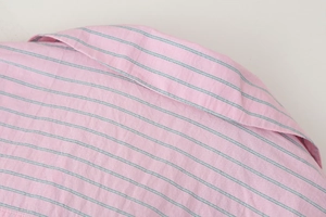 Détail du tissu en popeline de coton à rayures roses montrant les coutures fines