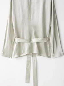 Dettaglio posteriore del blazer in raso con cintura in vita e trama liscia ed elegante