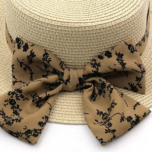 Close-up of woven straw hat featuring a brown floral bow with intricate pattern detail