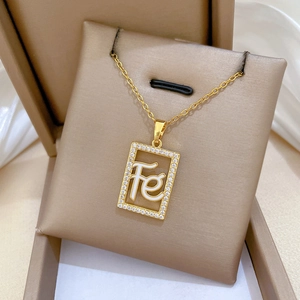 Detailed close-up of a gold-plated necklace with a crystal-encrusted FE square pendant
