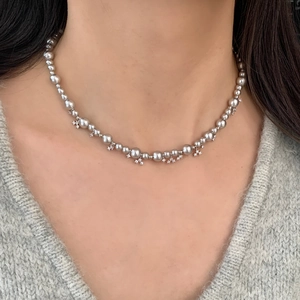 Detail of silver grey pearl necklace with tiny zircon flower pendants on knitwear