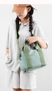 Close-up of mint green canvas handbag with durable webbing handles and front pocket detail