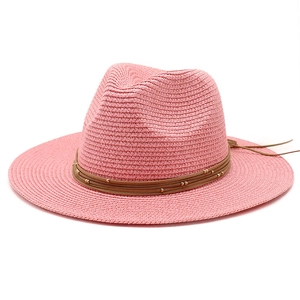 Pink straw Panama hat with woven detail, brown beaded cord, and wide sun shade brim