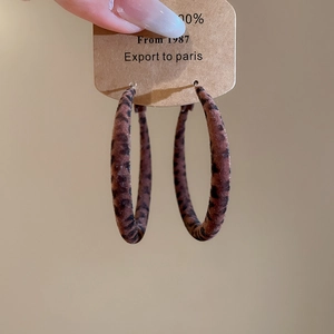 Détails de créoles floquées à motif léopard avec texture en tissu sur carte kraft