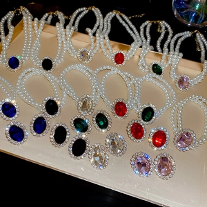 Macro shot of oval gemstone jewelry sets with pearl necklaces on a gold tray