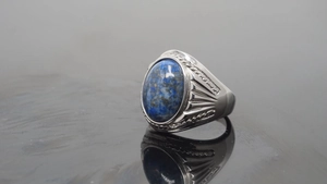 Macro detail of vintage silver ring with oval blue lapis lazuli and engraved patterns