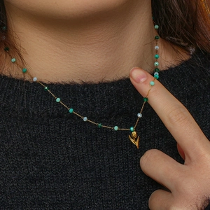 Détail du collier pendentif tulipe avec perles colorées porté sur un pull noir