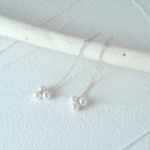 Detail of S925 silver fringe pearl drop earrings hanging on a wooden branch