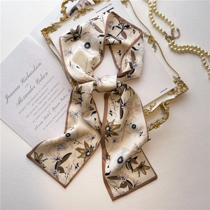 Detailed close-up of a vintage floral silk twilly scarf styled with elegant pearl jewelry