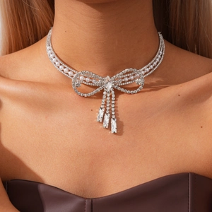 Close-up of elegant rhinestone bow necklace with pearl tassels on a female model