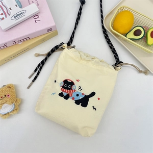 Detailaufnahme der cremefarbenen Canvas-Beuteltasche mit süßer Katzenstickerei und Kordel
