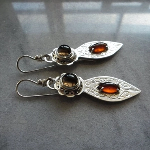 Dettaglio di orecchini vintage in argento con motivi incisi e pietre ambrate