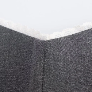 Detailed close-up of grey knit fabric neckline featuring delicate white lace embroidery