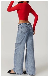 Detail of light blue wide-leg jeans with distressed rip and classic back pocket stitching