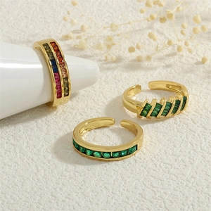 Detailed view of three 18K gold plated rings with zircon stones on a white surface