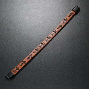 Close-up of brown braided leather bracelet featuring a black cross and magnetic clasp