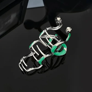 Detailed close-up of a silver snake-shaped hair claw clip with green enamel accents