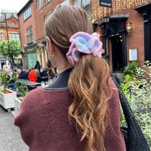 Detail of pink and blue knitted ruffle hair scrunchie worn on a model in urban setting