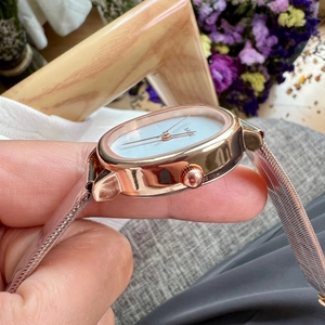 Detail of rose gold mesh strap and square case on a minimalist women's watch