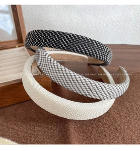 Three textured sponge headbands in plaid and solid beige displayed on a wooden surface