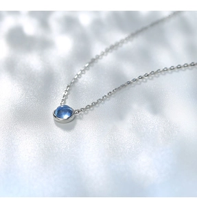 Dettaglio macro della collana in argento S925 con ciondolo tondo in gemma blu e catena fine