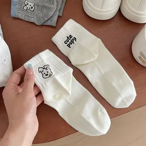 Close-up of white ribbed cotton socks featuring cute puppy embroidery and letter design