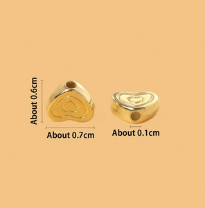 Macro shot of gold CCB heart-shaped beads showing 0.7x0.6cm dimensions and 0.1cm hole detail