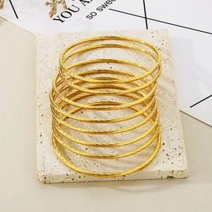 Close-up of stacked gold twisted cable bangles with intricate spiral texture on stone