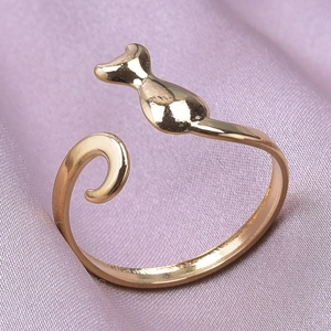 Close-up of golden adjustable cat ring with cat head and tail on purple velvet