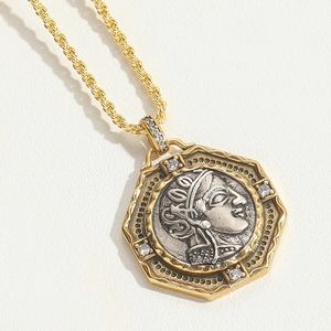 Macro shot of two-tone octagonal coin pendant with silver relief on a golden chain