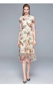 Close-up of delicate multi-color floral embroidery on beige mesh luxury dress