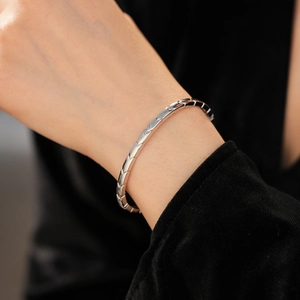Close-up of a silver geometric scale textured bangle on a model showing metallic luster
