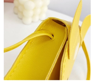 Detail showing the top opening and shoulder strap connection of the yellow cat kid bag