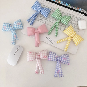 Flat lay of colorful quilted bow charms with cotton texture on a white workspace desk