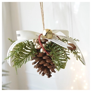 Close-up of Christmas pine cone hanging ornament with golden bell and white silk ribbon