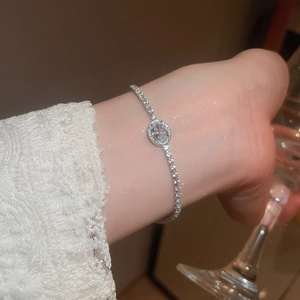 Detail of silver oval zircon bracelet worn by model with lace sleeves for elegant style