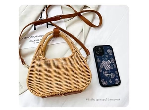 Detail of hand-woven rattan bag showing semi-circular handle and brown leather strap