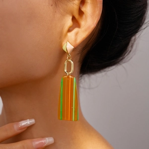 Detail view of resin geometric earrings with striped rectangular pendants on female model