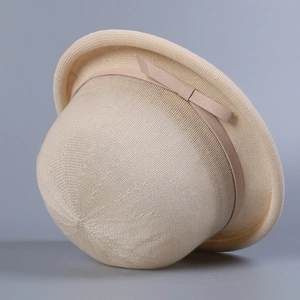 Detail of beige straw woven cloche hat with a delicate ribbon bow and fine knit texture