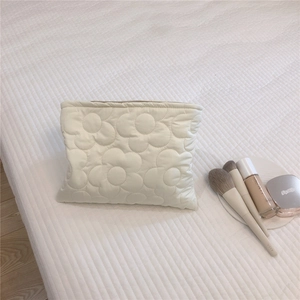 Macro view of white quilted down fabric with floral embroidery and top zipper closure