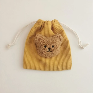 Detail of yellow corduroy drawstring bag with plush bear head and soft texture