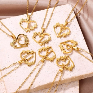 Dettaglio di collane con lettere a cuore dorato e accenti floreali sulla seta